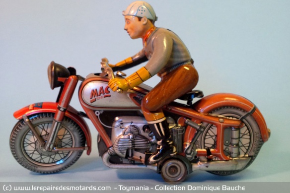 Moto Arnold Mc 700 : De marque allemande, cette célèbre moto de 1955 est ici présentée dans la version Jubilé (rouge) plus rare que la version noire de début 1950. Le pilote descend de sa moto losqu'elle s'arrête puis remonte en selle quelques instants pl