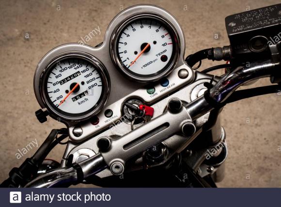 le-compteur-de-vitesse-a-fleche-d-une-moto-sur-le-volant-qui-se-trouve-sur-un-gros-plan-de-route-en-beton-tableau-de-bord-colore-d-une-moto-sport-vue-du-dessus-horiz-2d5jwf7.jpg