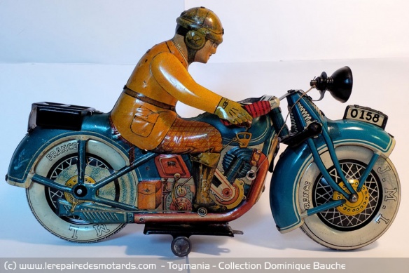 Moto bleue mécanique en tôle de marque JML (France). Circa 1930. Longueur: 30 cm. L'une des plus grandes motos existantes. Cette moto est rare à double titre : il s'agit de la première version, la moins courante. Elle est munie d'un éclairage électrique.